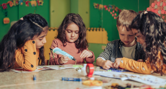 Rechtsanspruch Ganztagsschule Gruppe verschiedener Kinder, die mit einem elektronischen Konstrukteur spielen und ein digitales Gerät im Klassenzimmer verwenden.